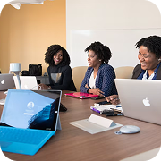 A diverse team of women smiling, using laptops during a productive meeting, effectively closing the loop on current tasks.