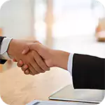 Business people shaking hands at a desk, signifying a new partnership for Investor Awareness and growth.